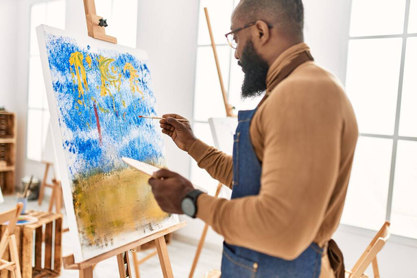 Joven afroamericano artista hombre sonriendo feliz dibujo en el estudio de arte. - Foto, imagen