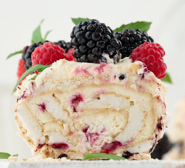 Baked meringue roll with cream and fresh fruits on a white wooden board, delicious dessert - Foto, Imagen