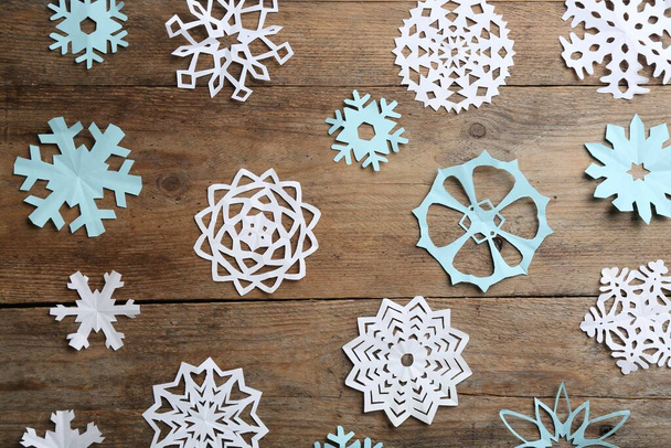 Many paper snowflakes on wooden background, flat lay - Zdjęcie, obraz