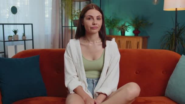 Displeased upset female girl reacting to unpleasant awful idea, dissatisfied with bad quality, wave hand, shake head No, dismiss idea, dont like proposal at home. Young woman sitting on orange sofa - Materiał filmowy, wideo