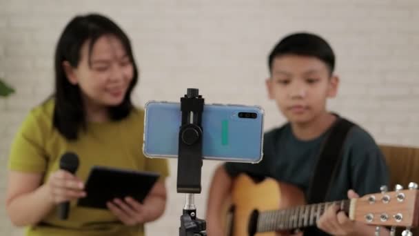Mother and son sang and played music together and recorded videos on their smartphones. Online music concept. Online music performances. Family relationship activities - Video
