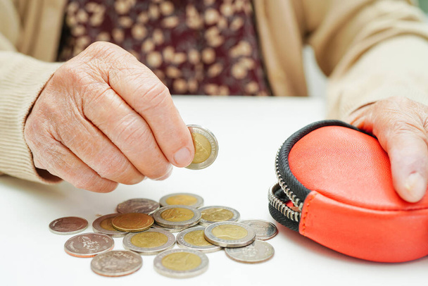 Retired elderly woman counting coins money and worry about monthly expenses and treatment fee payment. - Фото, изображение