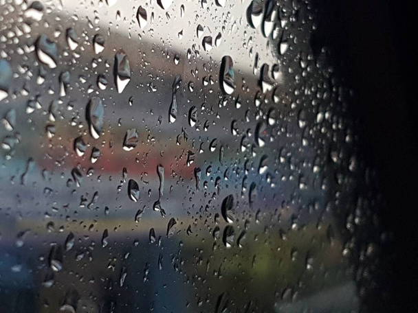 Water droplets on surface of car glass window. Car wash concept. Natural patterns of droplets on windshield. Rain drops wallpaper. Wet windscreen shot during car wash. Selective focus - Foto, afbeelding