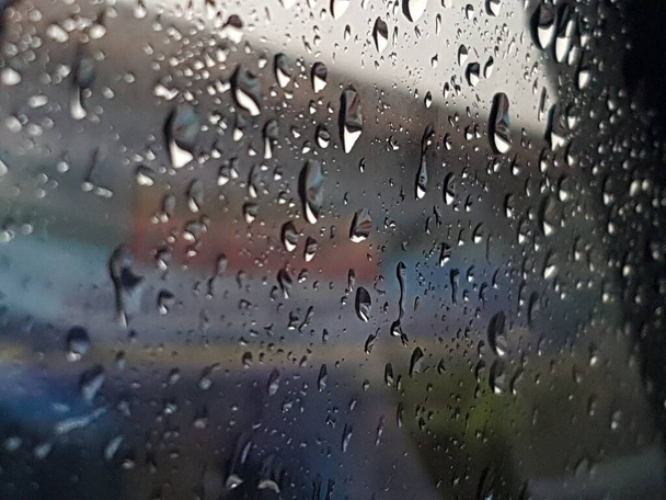 Water droplets on surface of car glass window. Car wash concept. Natural patterns of droplets on windshield. Rain drops wallpaper. Wet windscreen shot during car wash. Selective focus - Photo, image