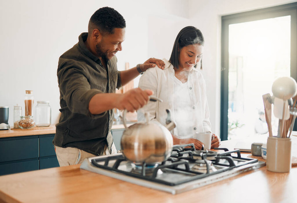 Loving couple having coffee or tea, relaxed and carefree while bonding in a kitchen at home. Caring husband being affectionate, talking and enjoying their relationship and quiet morning with his wife. - 写真・画像