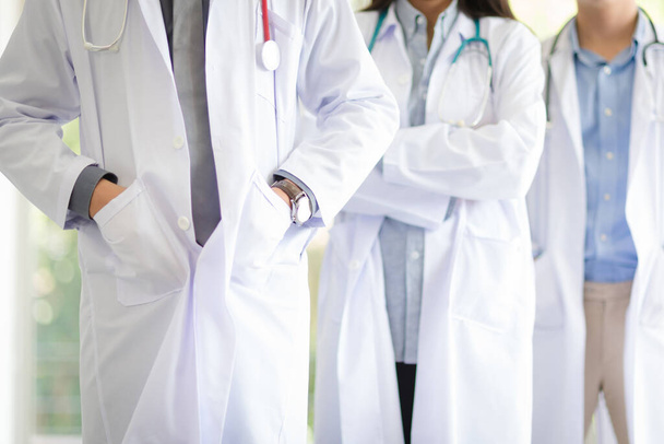 Группа азиатских врачей команда портрет в белом халате профессиональная униформа стоя с коллегами на заднем плане. - Фото, изображение