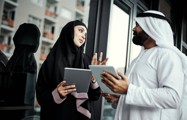 The ideas are flowing. two young businesspeople dressed in Islamic traditional clothing using their tablets on the office balcony - Zdjęcie, obraz