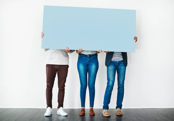Say whats on your mind. Studio shot of a group of people covering themselves with a blank placard against a white background - Fotoğraf, Görsel