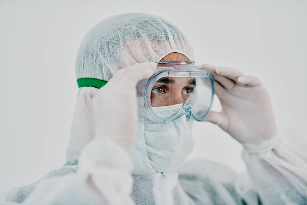 Healthcare worker wearing protective hazmat suit during covid virus outbreak. Medical research professional in a quarantine zone preparing for sanitizing and staying safe during pandemic restrictions. - Foto, immagini