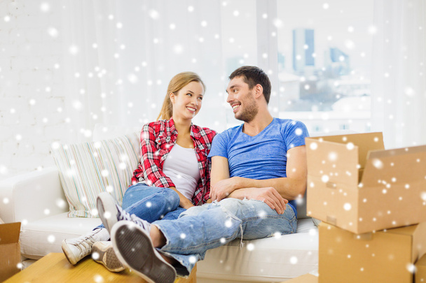 smiling couple relaxing on sofa in new home - 写真・画像