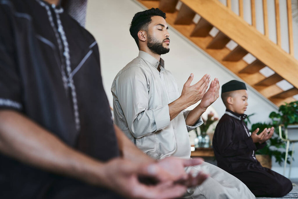 Muslim family praying together at home with eyes closed during fajr, dhuhr, asr, maghrib or Isha. Practicing religion and cultural tradition to serve or worship the god of their faith and belief. - Fotó, kép