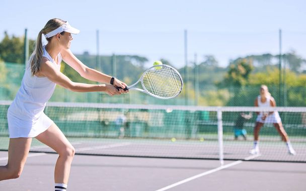 Sports and active tennis player hitting ball with racket equipment during a competitive match or hobby activity on a court. Athletic, sporty and fit woman playing in a tournament game with sportswear. - Photo, Image