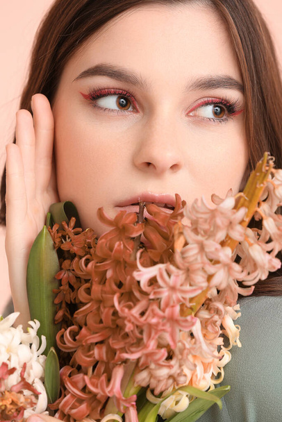 Hermosa mujer joven con flores de jacinto sobre fondo de color, primer plano - Foto, imagen