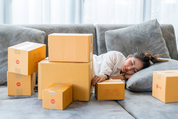 Piękne azjatyckie kobiety spać na kanapie z wielu paczek box z małych firm sprzedają do klienta na zakupy online. - Zdjęcie, obraz