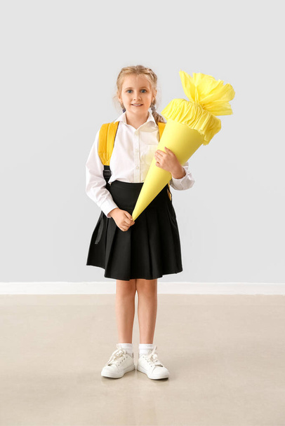 Cute little girl with yellow school cone near light wall - Zdjęcie, obraz