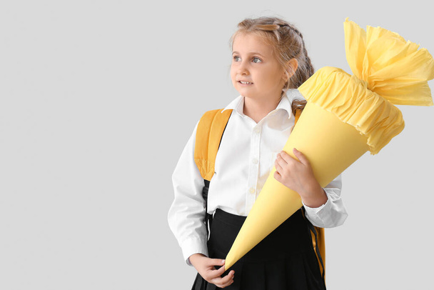 Cute little girl with yellow school cone on light background - Fotografie, Obrázek