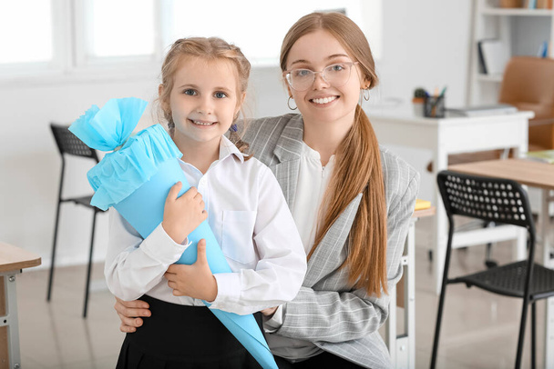 Cute little girl with blue school cone and her teacher in classroom - Fotografie, Obrázek