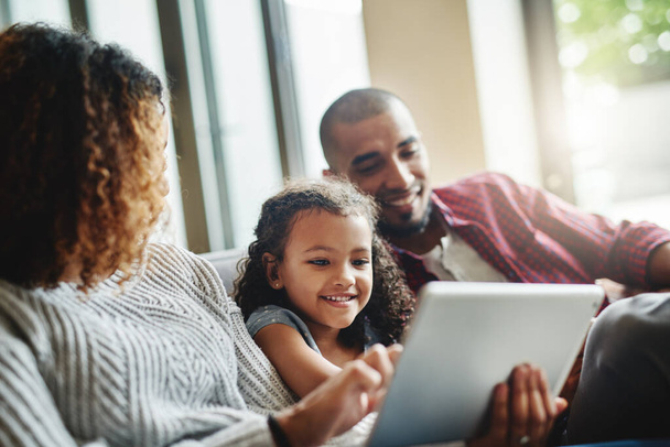 Шеш насолоджується цим онлайн досвідом. чарівна маленька дівчинка використовує цифровий планшет зі своїми батьками у своїй вітальні вдома
 - Фото, зображення