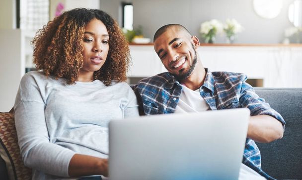 Technology gives couples more ways to connect. a young couple relaxing on the sofa at home and using a laptop together - Foto, Imagen