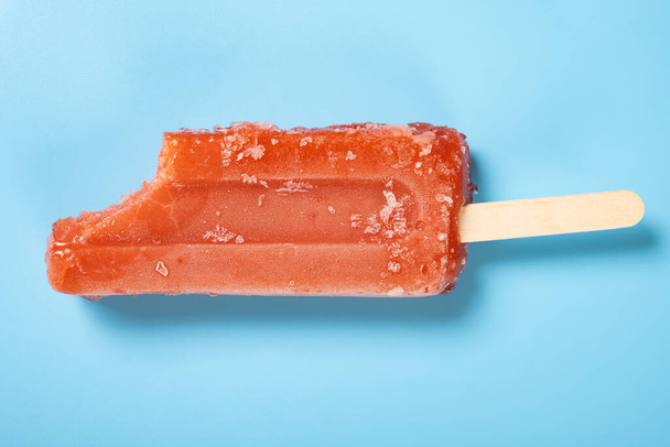 top view fresh red popsicle with a bite on a blue background - Foto, afbeelding