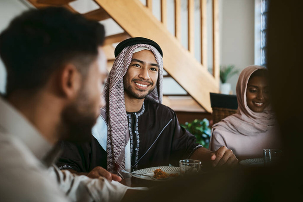 Muslim, arab and islamic man enjoying a meal for eid, ramadan or breaking fast with family while celebrating religion, holy culture and islam faith. Happy, smiling and spiritual guy eating lunch. - Foto, Imagen