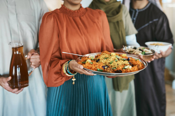 Ramadan, Eid and iftar with a muslim family holding food and drink to break their fast at home together. Closeup of rice and curry in the hands of a woman with people holding other meals and juice. - Photo, image