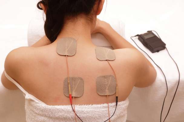 Mujer asiática está haciendo masaje de estimulación eléctrica (TENs
 ) - Foto, imagen