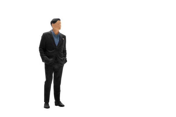 Miniature people businessman wearing black suit standing isolated on white background with clipping path - Foto, Bild