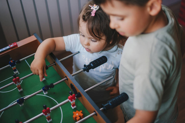 Boy and baby girl learning how to play table football. Children play table football. Games in the room. - Фото, зображення