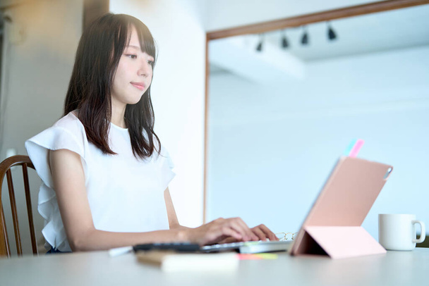 Азиатская молодая женщина работает планшетный компьютер в комнате - Фото, изображение