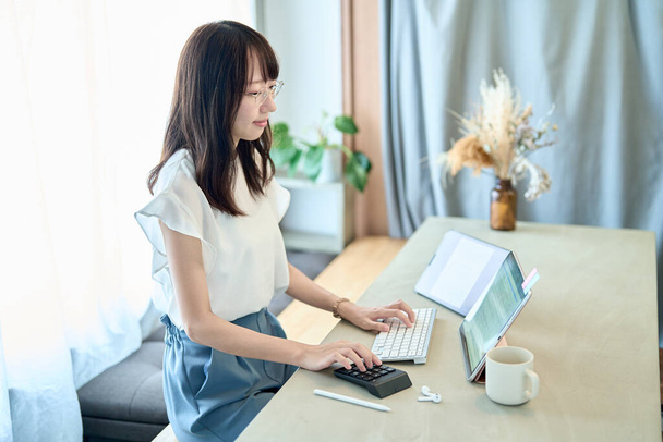 A woman wearing glasses and operating a tablet PC - 写真・画像