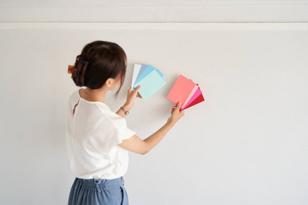 θηλυκό συντονιστής εσωτερικών χώρων εξέταση χρώματος τοίχου - Φωτογραφία, εικόνα