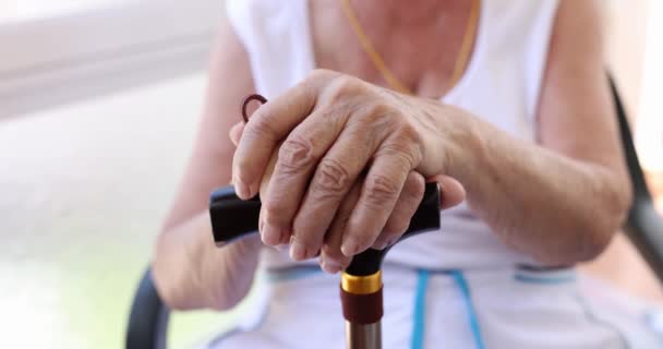 Κοντινό ξύλινο μπαστούνι σε ζαρωμένα χέρια άγνωστου άρρωστου ώριμου πολίτη. Υγεία ηλικιωμένων ατόμων με χρόνιες παθήσεις που ζουν με αναπηρίες - Πλάνα, βίντεο