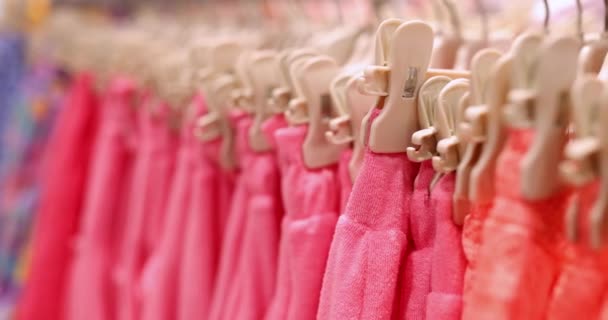 Bright pink women shorts and pants hanging on hangers on rack in clothing store. Shopping buying women clothing - 映像、動画