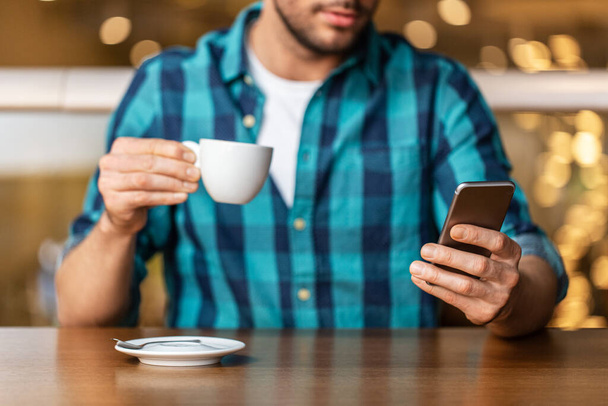 people, technology and leisure concept - close up of man drinking coffee and messaging on smartphone at restaurant or cafe - Φωτογραφία, εικόνα