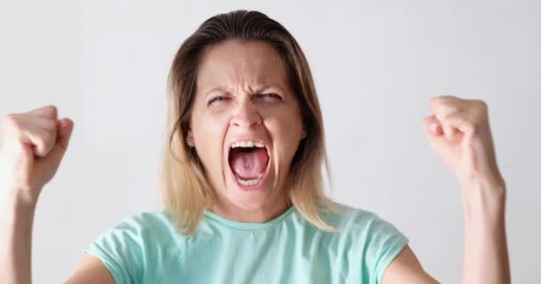 Portrait of beautiful young caucasian woman screaming in anger directly at camera. Girl in agony expresses her negative evil emotions - Felvétel, videó