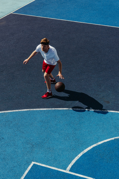high angle view of young sportsman playing basketball on court - 写真・画像