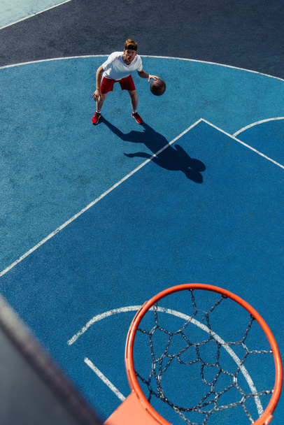 high angle view of young sportive man training on basketball court - Zdjęcie, obraz
