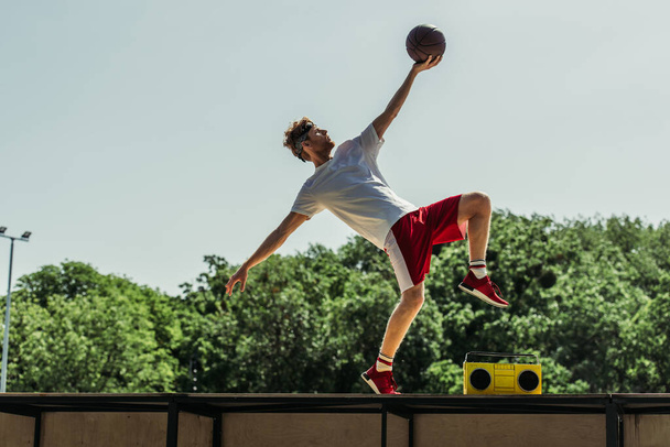 πλαϊνή άποψη του ανθρώπου στα αθλητικά παίζει μπάσκετ κοντά στο πικάπ - Φωτογραφία, εικόνα