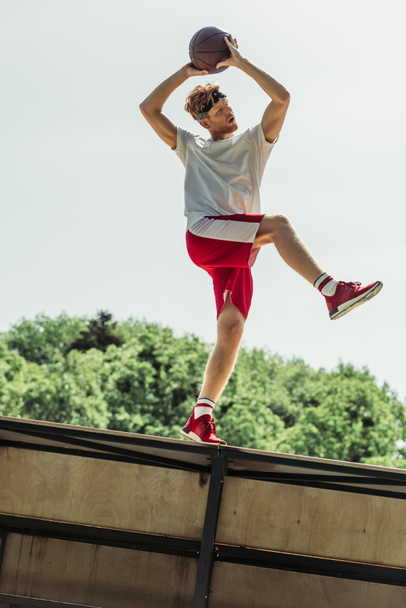 low angle view of sportive man playing basketball outdoors in summer - Fotografie, Obrázek