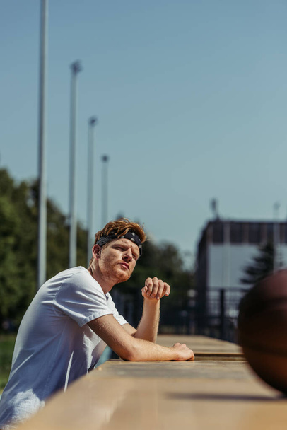 young sportive man in bandana and white t-shirt looking away outdoors - Fotó, kép