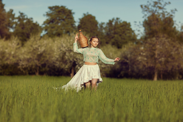 Chica con una jarra está en el campo con hierba
. - Foto, Imagen