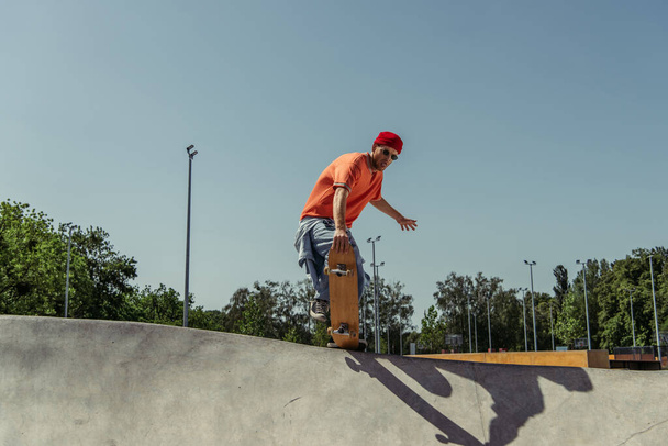 young skateboarder in sunglasses jumping from ramp in skate park - Foto, afbeelding