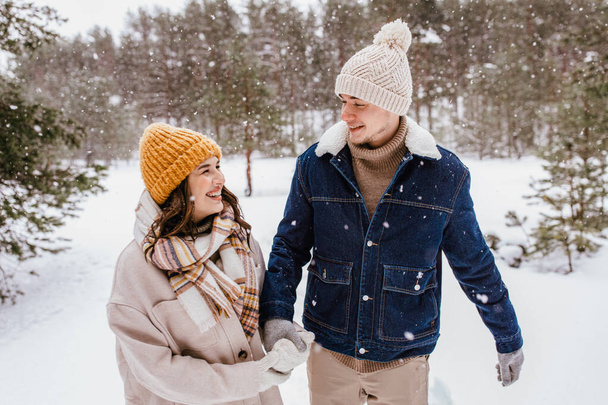 people, love and leisure concept - happy smiling couple walking in winter forest - Valokuva, kuva