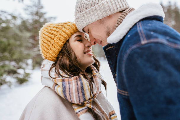 people, love and leisure concept - happy smiling couple touching noses in winter park - Фото, изображение