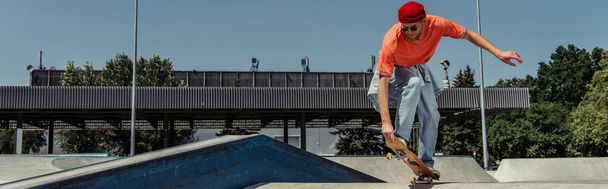 trendy man in sunglasses jumping with skateboard while training in park, banner - Foto, Imagem