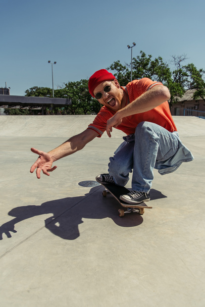 thrilled man gesturing while skateboarding in park - Fotó, kép