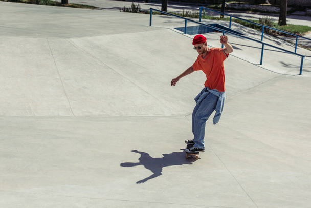 full length of fashionable young man riding skate outdoors - Photo, Image