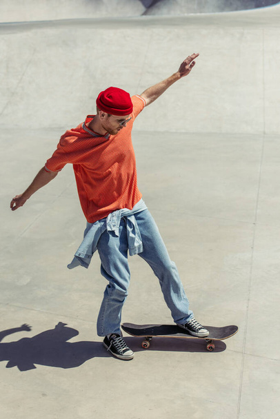 full length of stylish man with outstretched hands skateboarding in skate park - 写真・画像