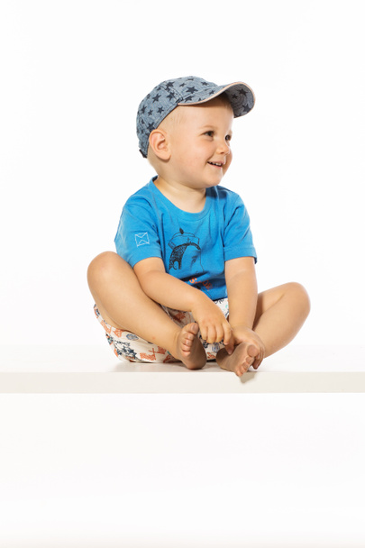 Blond smiling boy sitting on the table wearing baseball cap - Fotografie, Obrázek